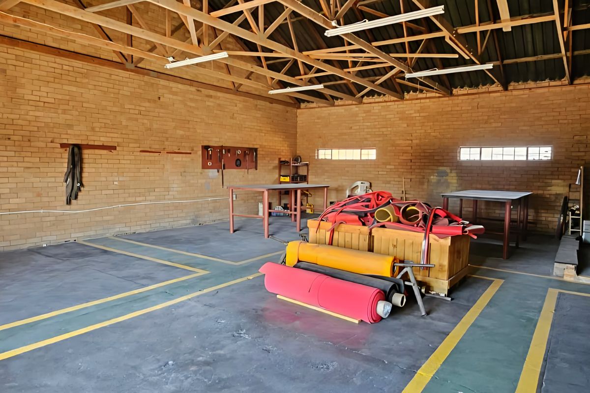 Spacious industrial utility area featuring exposed timber roof trusses, brick walls, and durable concrete flooring with painted safety markings.