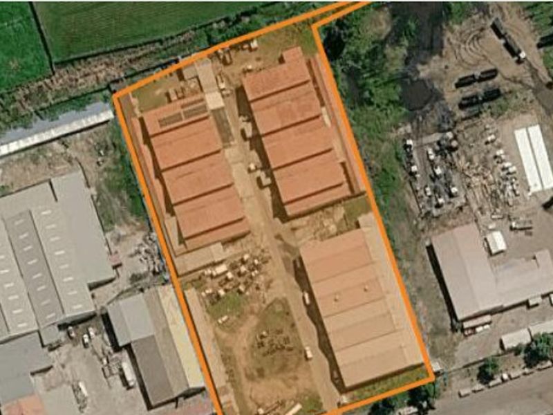 Aerial view of a commercial industrial complex featuring multiple warehouse structures and paved access areas within a defined perimeter.