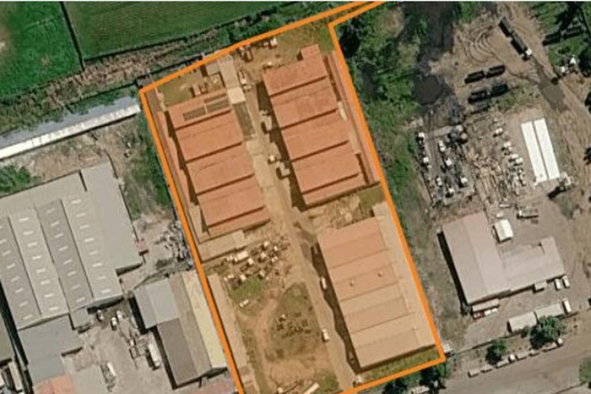 Aerial view of a commercial industrial complex featuring multiple warehouse structures and paved access areas within a defined perimeter.