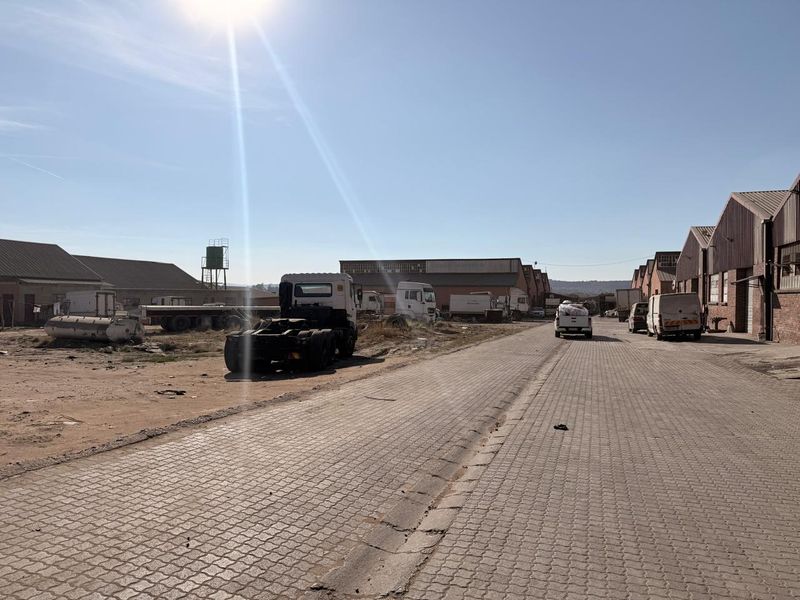 Exterior view of a commercial industrial property featuring paved access roads and multiple warehouse structures with an open yard area.