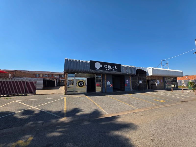 Front exterior view of a commercial retail property featuring a paved parking area, metal canopy, and glass storefront entrance.