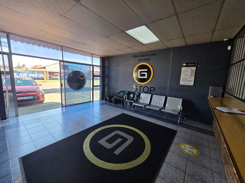 A commercial entry and reception area featuring tiled flooring, a drop ceiling with recessed lighting, and a large glass storefront facade.