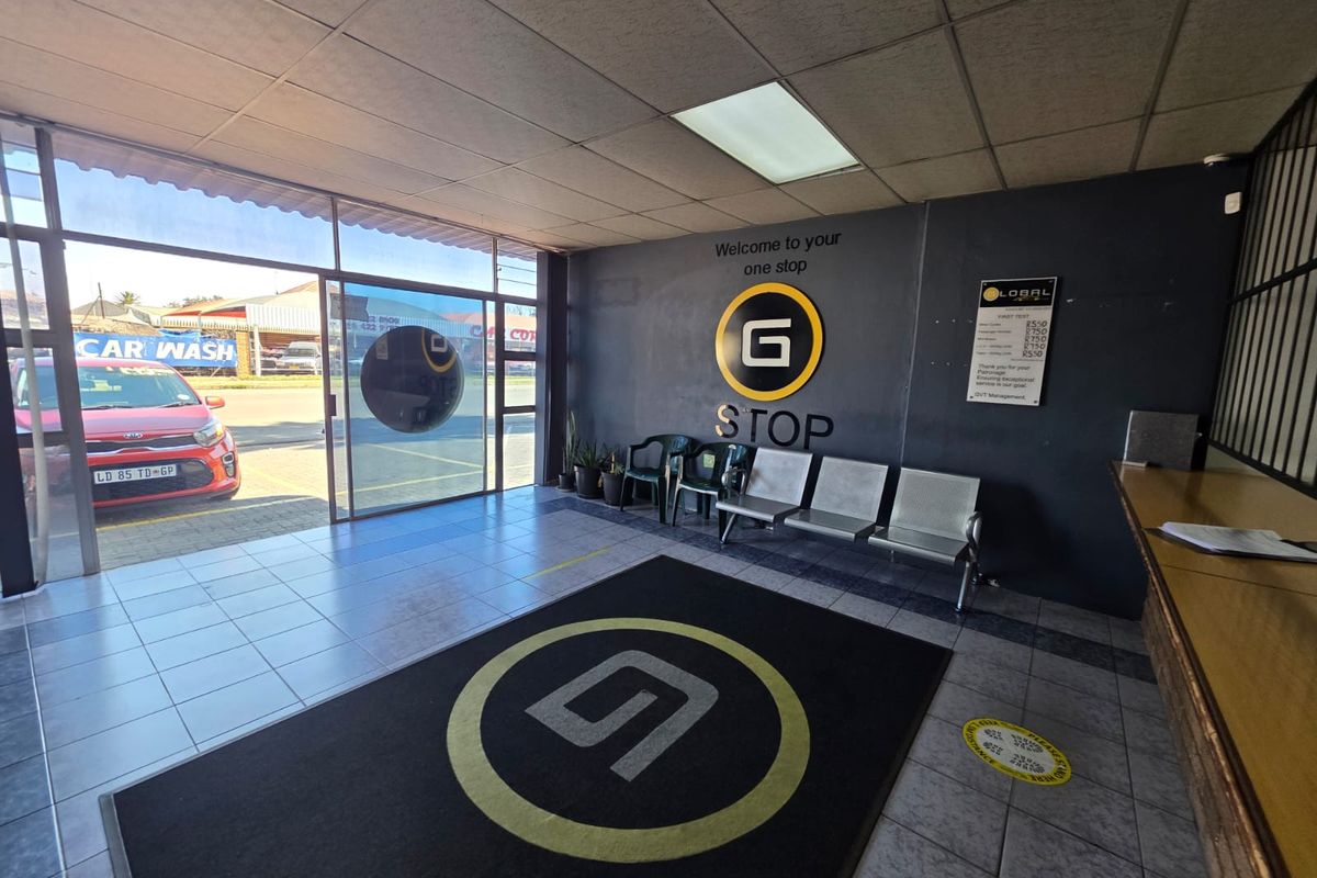 A commercial entry and reception area featuring tiled flooring, a drop ceiling with recessed lighting, and a large glass storefront facade.