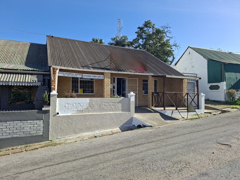 Front exterior view of a commercial office building featuring a brick facade, corrugated metal roof, and a concrete access ramp with timber railing.