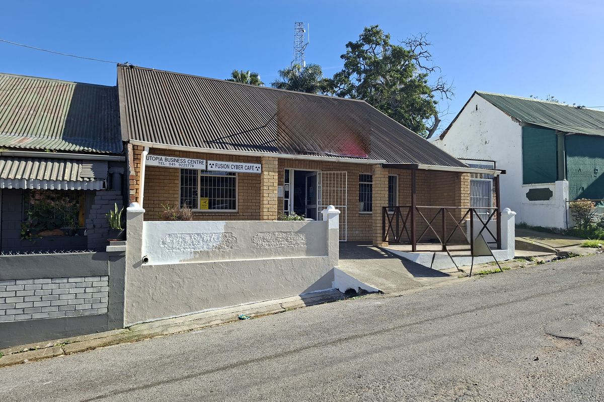 Front exterior view of a commercial office building featuring a brick facade, corrugated metal roof, and a concrete access ramp with timber railing.