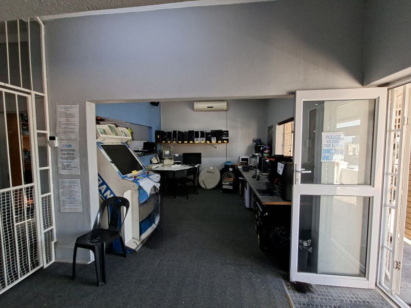 A functional office space featuring carpeted flooring, a split-system air conditioner, and a secure glass entrance door.