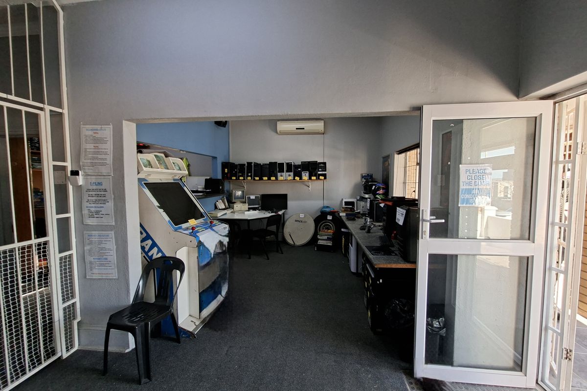 A functional office space featuring carpeted flooring, a split-system air conditioner, and a secure glass entrance door.