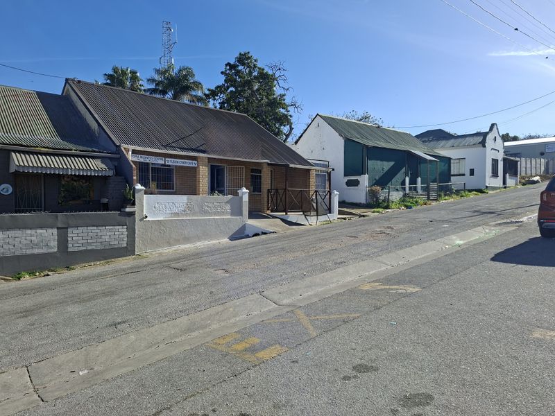 Street view of a commercial office building featuring a corrugated metal roof, brick facade, and secure entrance gates.