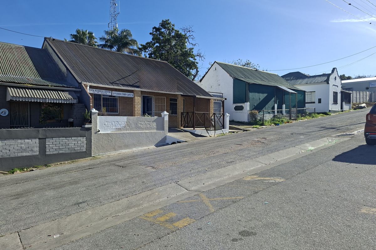 Street view of a commercial office building featuring a corrugated metal roof, brick facade, and secure entrance gates.