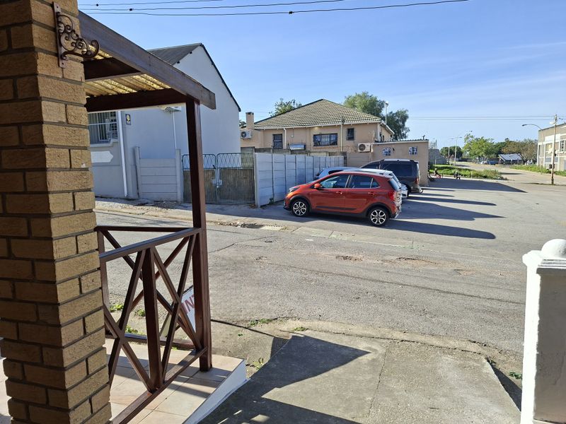 Street view showing the property entrance, featuring a timber pergola structure, brick pillar, and concrete driveway access.