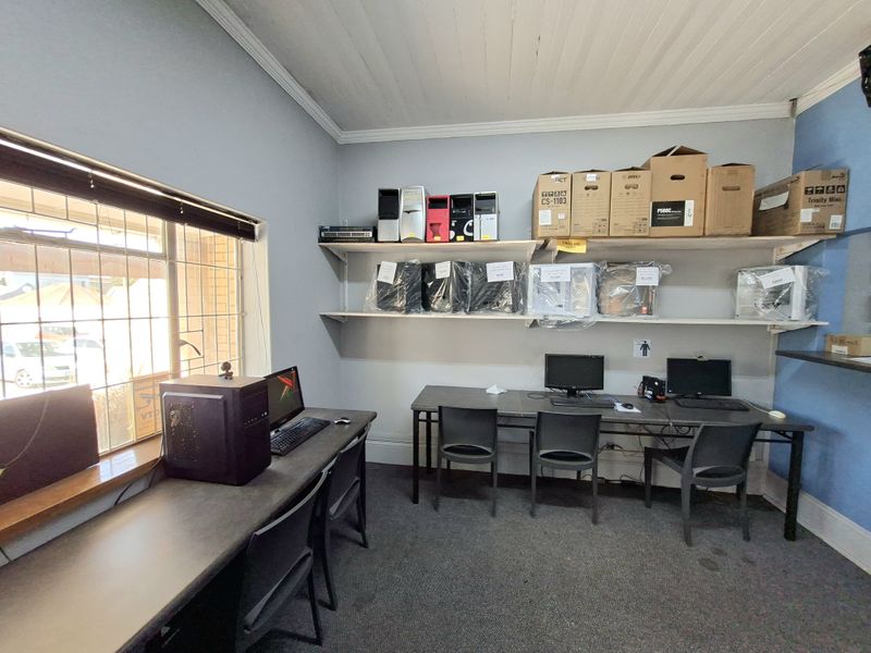 Functional office space featuring built-in shelving units, security window bars, and a timber ceiling, suitable for a professional work environment.