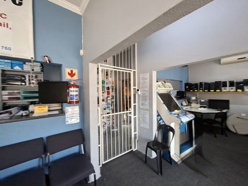 Office interior featuring a security gate, built-in shelving, and an air conditioning unit, with blue painted walls and carpeted flooring.