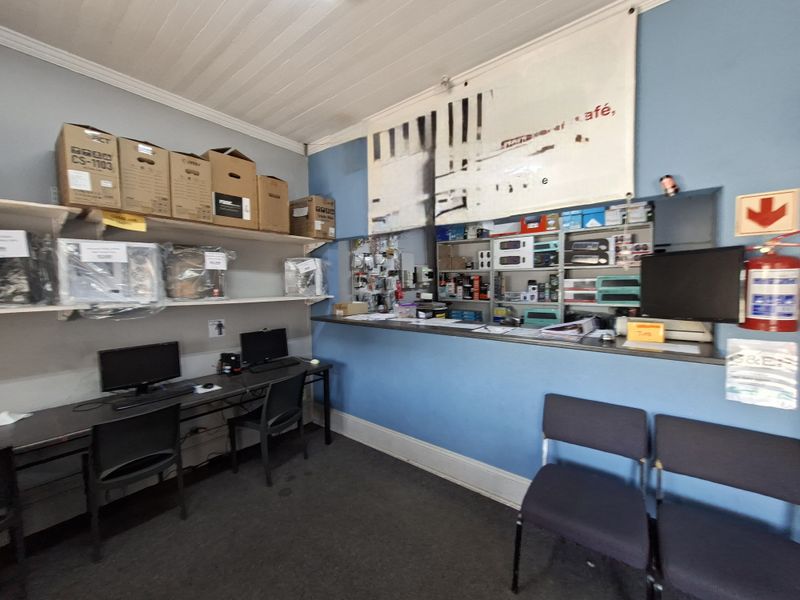 Office space featuring a service counter, wall-mounted shelving units, and a timber ceiling, suitable for retail or administrative operations.