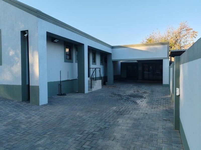 A well-maintained office exterior featuring a paved driveway, secure boundary walls, and modern external lighting fixtures.