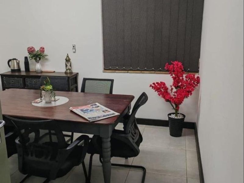 A functional office space featuring tiled flooring, a window with vertical blinds, and a ceiling ventilation unit.