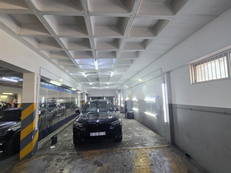 A functional commercial garage space featuring a waffle slab ceiling, industrial lighting, and concrete flooring, suitable for vehicle maintenance or storage.
