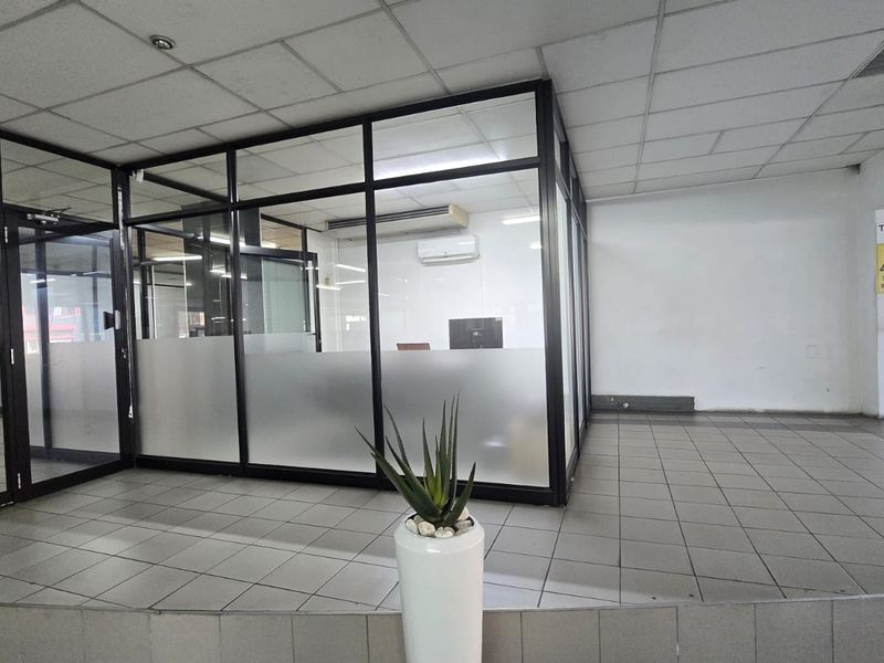 A vacant commercial office space featuring glass partitioning, suspended ceilings, and tiled flooring, suitable for a professional workspace or reception area.