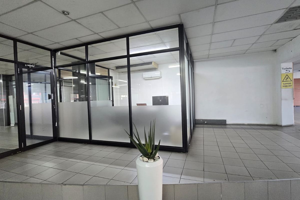 A vacant commercial office space featuring glass partitioning, suspended ceilings, and tiled flooring, suitable for a professional workspace or reception area.