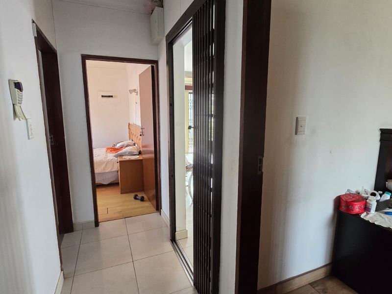 A functional hallway featuring tiled flooring and a sliding security gate, providing access to adjacent rooms within the commercial property.
