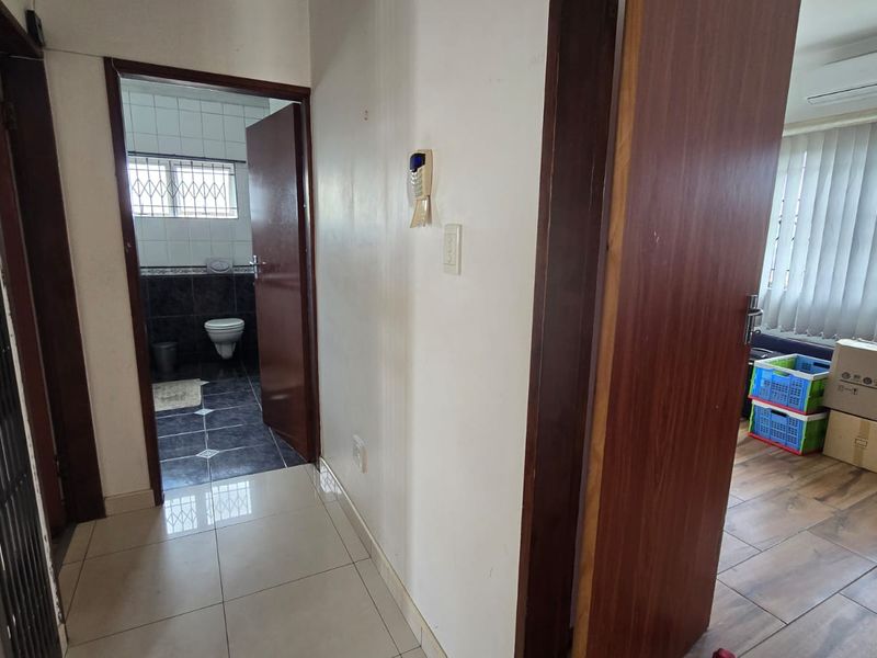 A functional hallway connecting to a bathroom and an adjacent room, featuring tiled flooring and access to internal spaces.