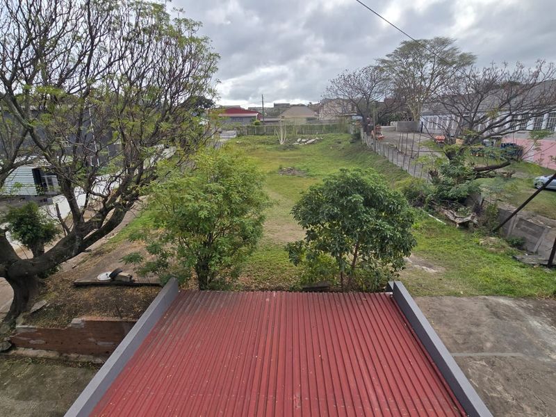 An elevated aerial view of the property grounds, featuring a corrugated metal roof in the foreground and an expansive, undeveloped rear yard area.