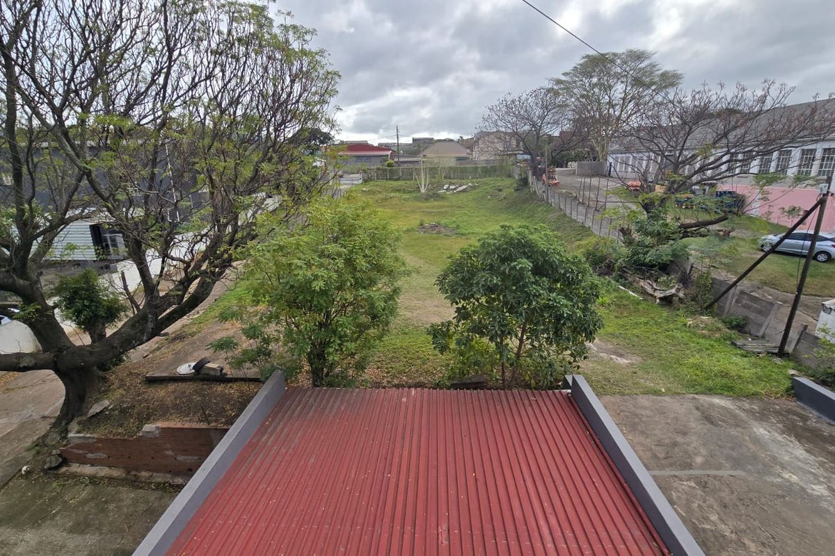 An elevated aerial view of the property grounds, featuring a corrugated metal roof in the foreground and an expansive, undeveloped rear yard area.