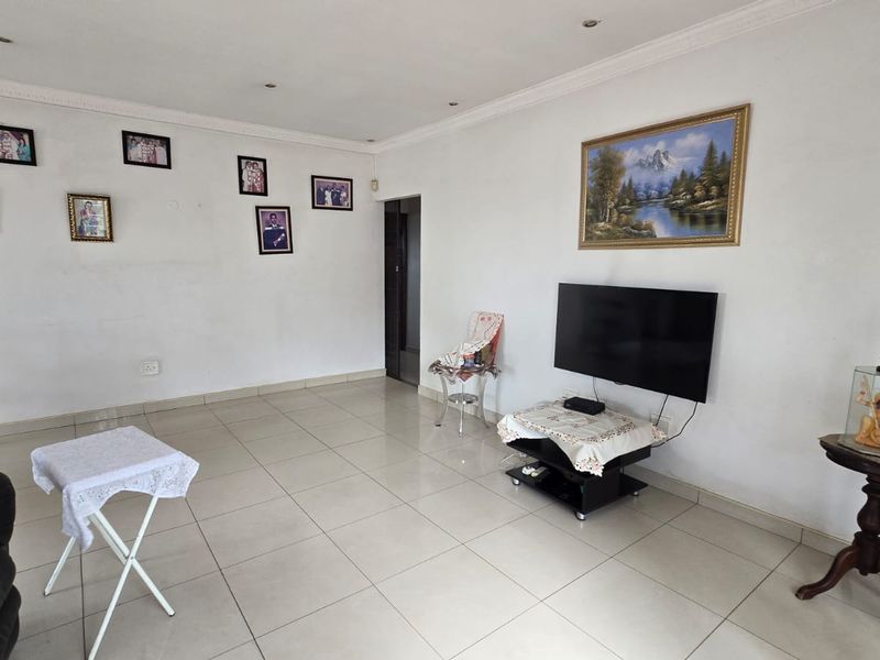 A spacious living area featuring neutral tiled flooring, recessed ceiling lighting, and decorative coving, providing a clean and functional foundation for interior design.