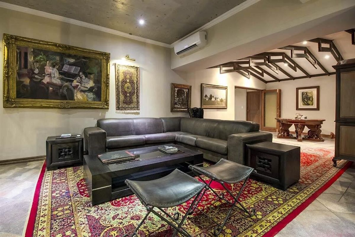 Spacious living area featuring exposed timber ceiling beams, tiled flooring, and a wall-mounted split-system air conditioning unit.