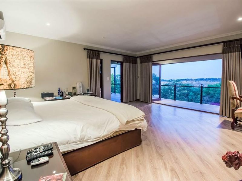 Spacious bedroom featuring light wood-look laminate flooring, recessed lighting, and direct access to a private balcony with scenic views.