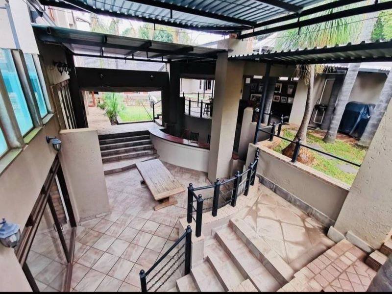 A multi-level covered outdoor patio area featuring a built-in bar, tiled flooring, and metal structural roofing, ideal for outdoor entertaining.