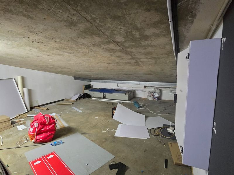 An unfinished utility or storage space featuring an exposed concrete ceiling and a wall-mounted electrical distribution board.