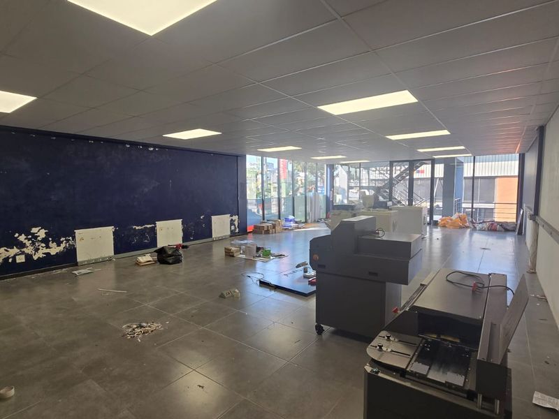 Spacious open-plan commercial unit featuring tiled flooring, suspended ceiling with recessed lighting, and large glass windows providing ample natural light.