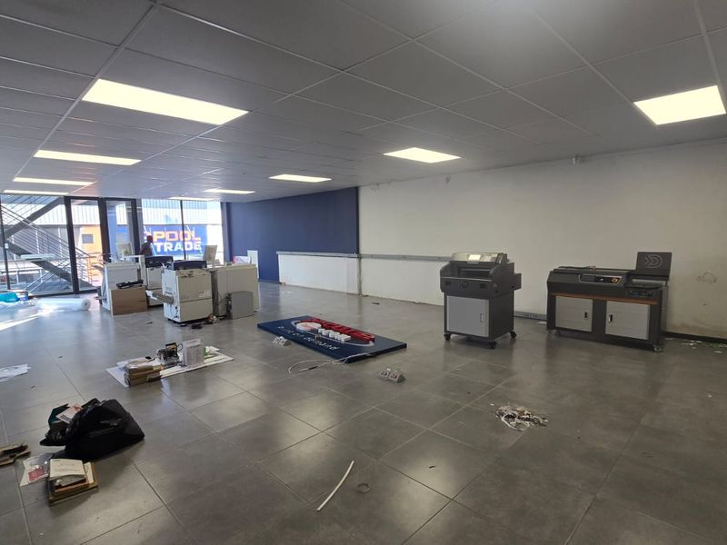 Spacious commercial office or retail space featuring tiled flooring, suspended ceilings with recessed lighting, and large glass windows providing ample natural light.