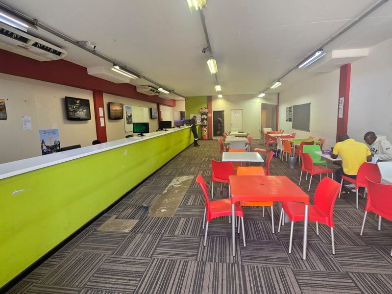 Open plan commercial space featuring a long service counter, carpeted flooring, and functional lighting, suitable for a betting shop or retail service environment.