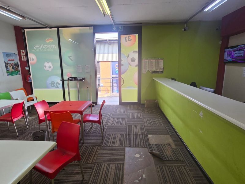 Open plan commercial space featuring a built-in service counter, carpet tile flooring, and fluorescent lighting, suitable for a betting shop or retail office.