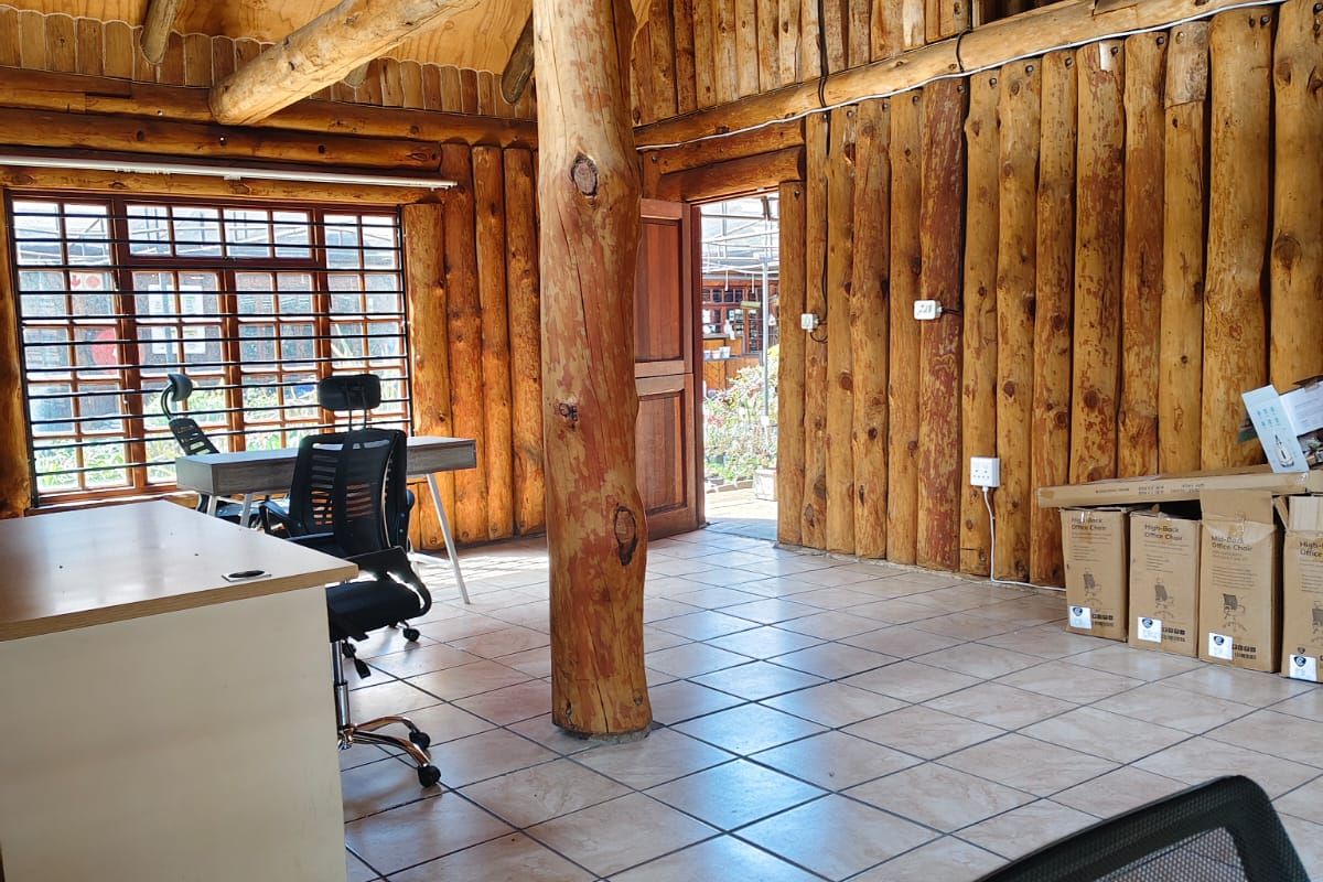 Rustic office space featuring exposed timber log walls, vaulted timber ceiling, ceramic tiled flooring, and a large central timber support column.