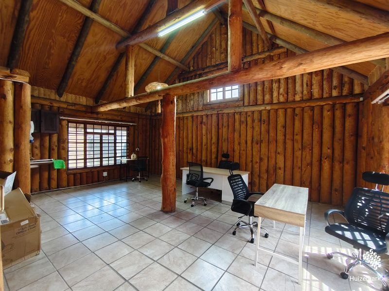 Spacious office area featuring rustic exposed log walls, high vaulted timber ceilings, and tiled flooring, providing a unique and characterful workspace.