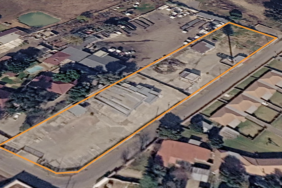 Aerial view of a large industrial property featuring multiple sheds, extensive yard space, and secure perimeter fencing.