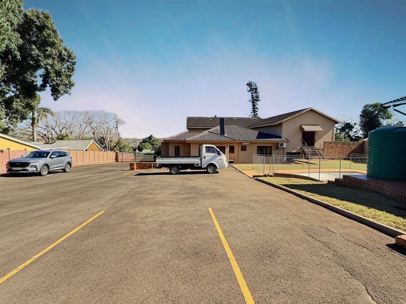 Rear exterior view of the commercial property featuring a paved parking area, perimeter fencing, and a water storage tank.