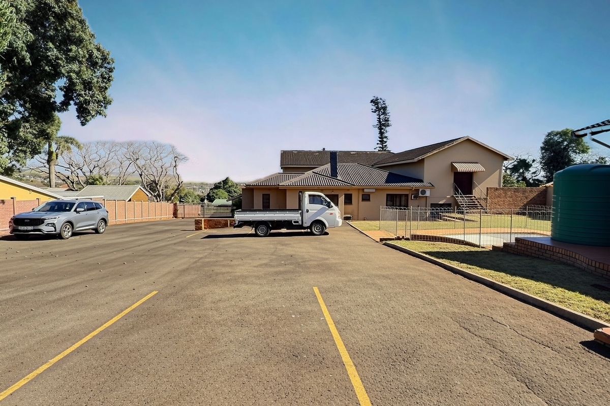 Rear exterior view of the commercial property featuring a paved parking area, perimeter fencing, and a water storage tank.