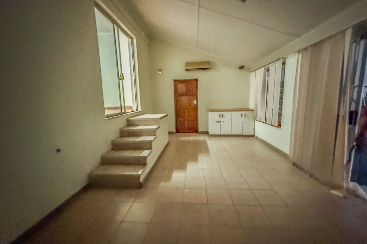 Spacious open-plan living area featuring tiled flooring, built-in cabinetry, split-system air conditioning, and an internal staircase leading to an elevated section.