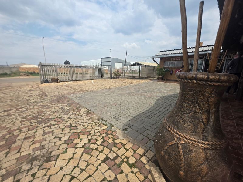 Exterior view of the restaurant entrance featuring a paved parking area, brick facade, and secure gated access.