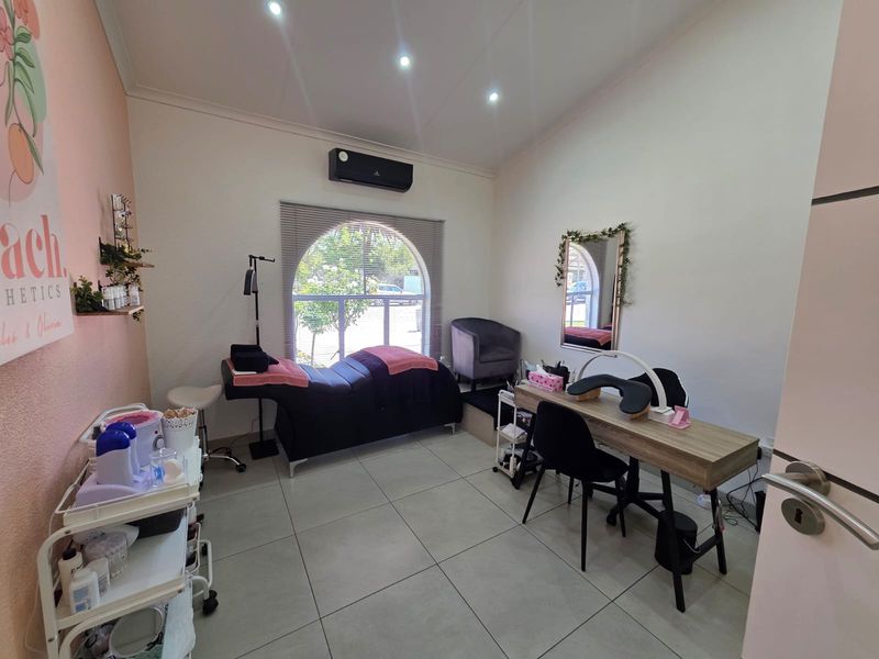A well-maintained office or treatment room featuring tiled flooring, recessed lighting, a split-system air conditioner, and a distinctive arched window.
