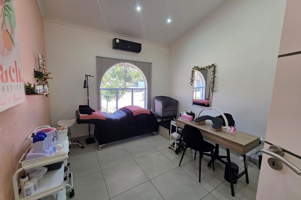 A well-maintained office or treatment room featuring tiled flooring, recessed lighting, a split-system air conditioner, and a distinctive arched window.