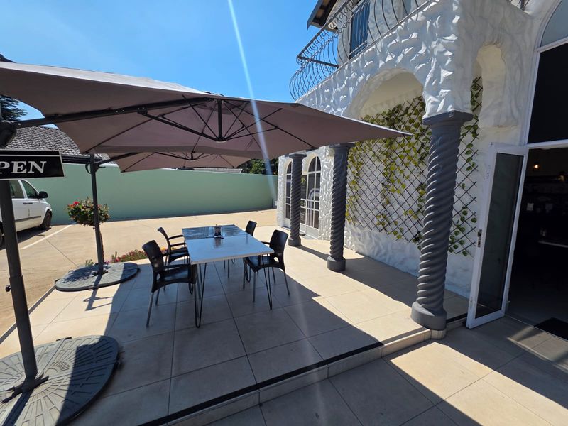 A well-maintained covered patio area featuring decorative columns and tiled flooring, providing an inviting outdoor space for retail customers.