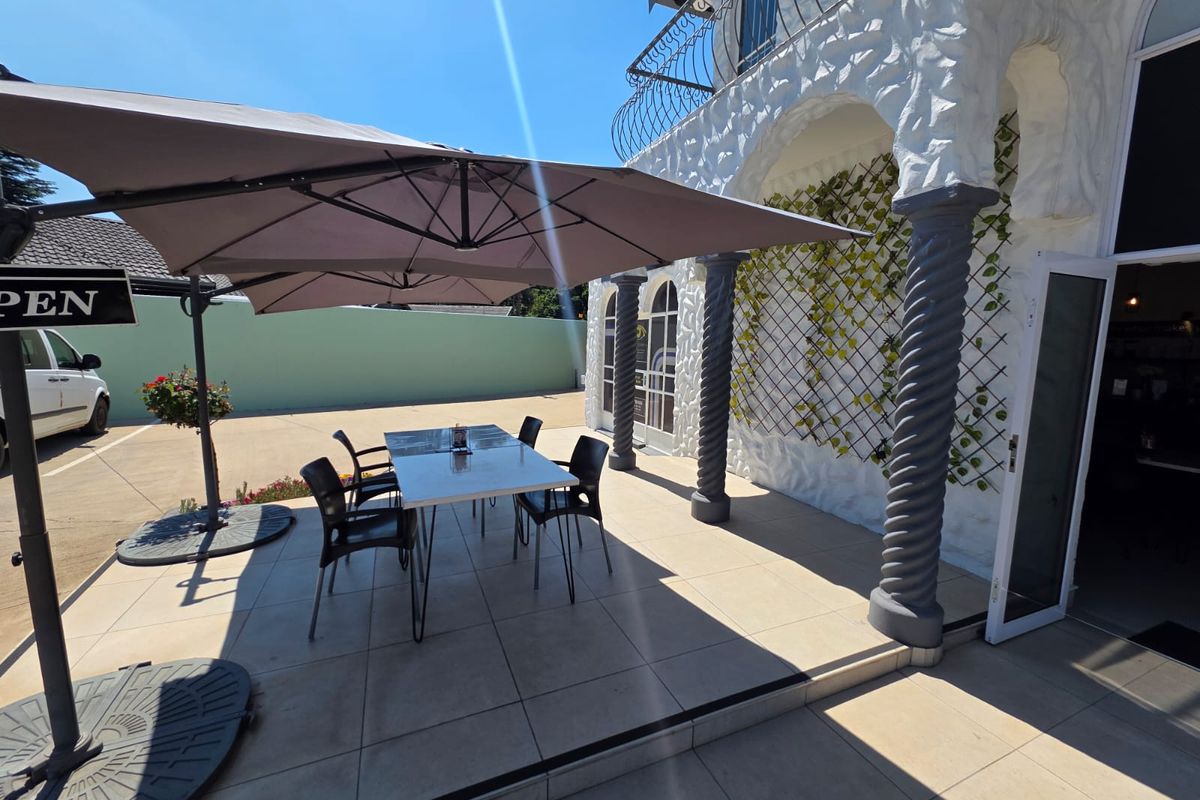A well-maintained covered patio area featuring decorative columns and tiled flooring, providing an inviting outdoor space for retail customers.