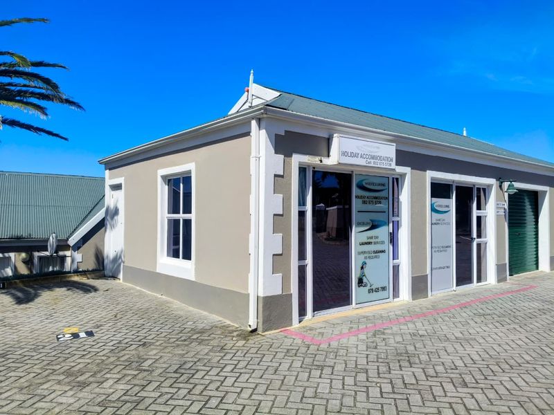 Exterior view of a commercial property featuring paved driveway access, aluminium framed glass entrance doors, and sash windows under a pitched roof.