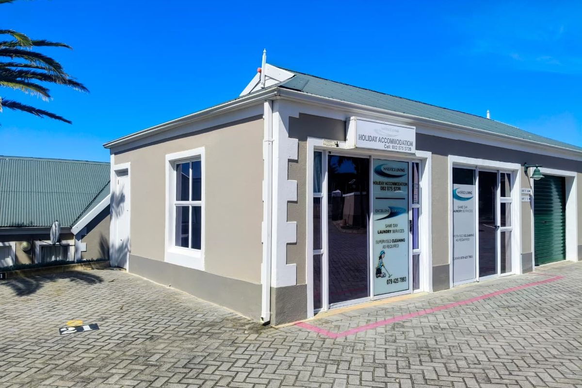 Exterior view of a commercial property featuring paved driveway access, aluminium framed glass entrance doors, and sash windows under a pitched roof.