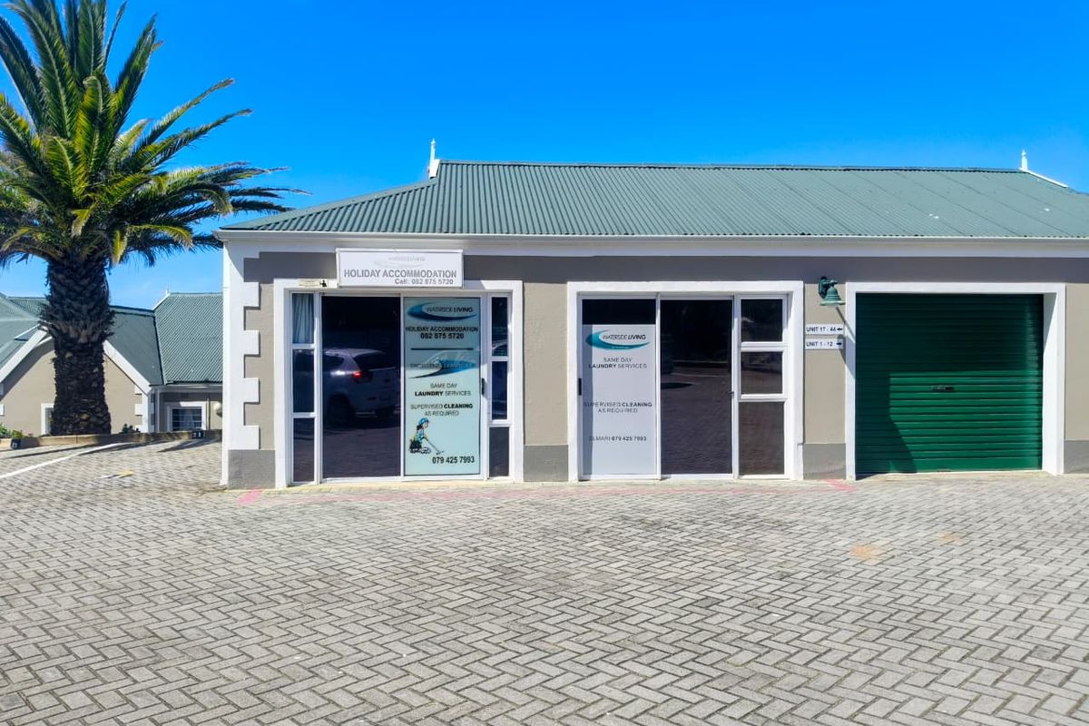 Front exterior view of a commercial property featuring a paved driveway, green metal roof, sliding glass entrance doors, and a secure garage.