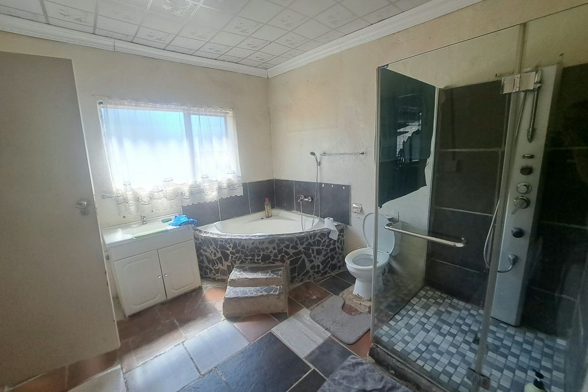 A dated bathroom featuring a corner bathtub, separate shower enclosure, vanity cabinet, and toilet, requiring cosmetic updates to improve its overall condition and appeal.